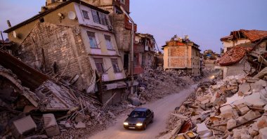 A car drives past collapsed buildings in Antakya, Hatay, southestern Türkiye, Feb. 20, 2023. (AFP Photo)