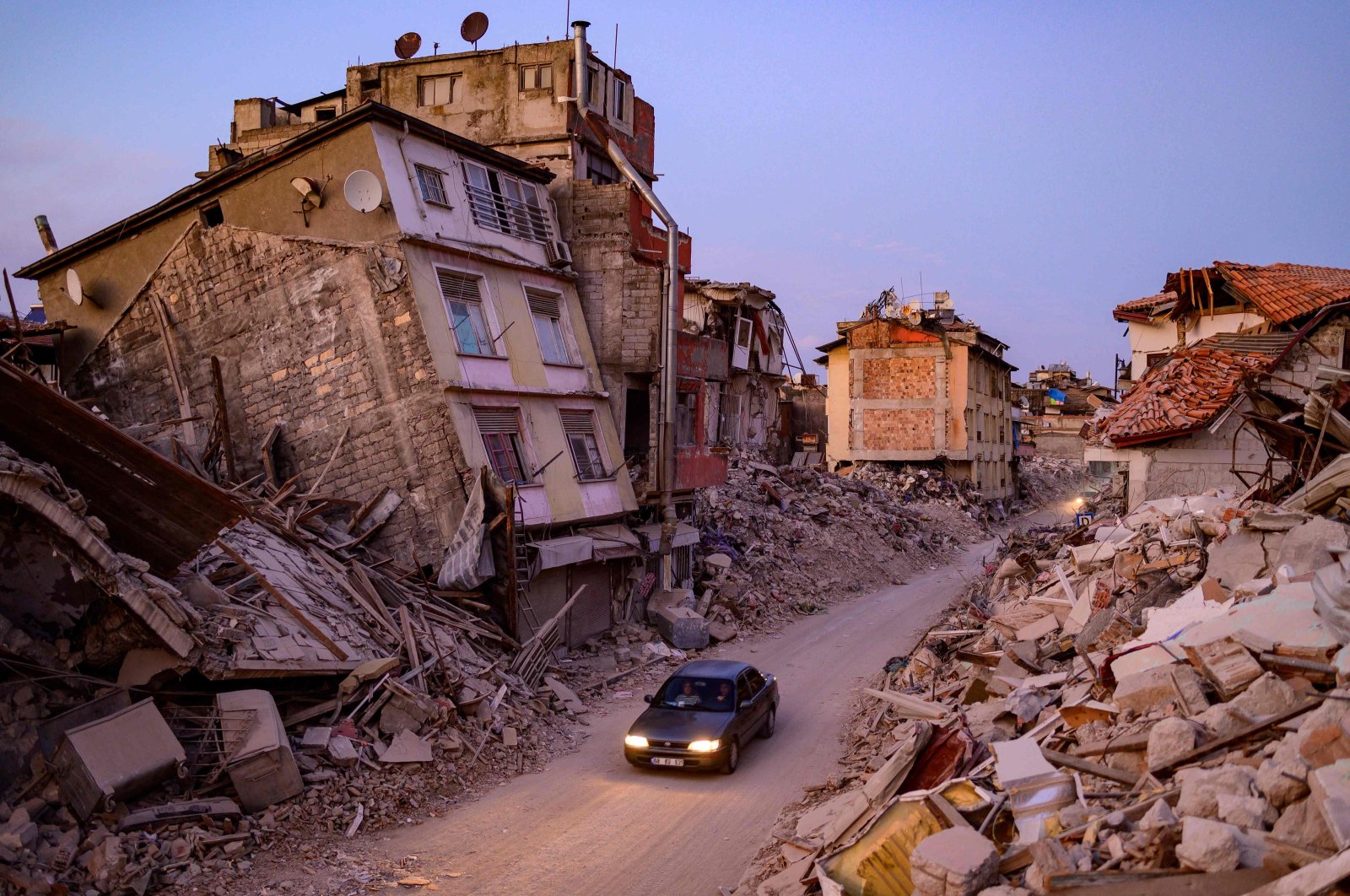 A car drives past collapsed buildings in Antakya, Hatay, southestern Türkiye, Feb. 20, 2023. (AFP Photo)