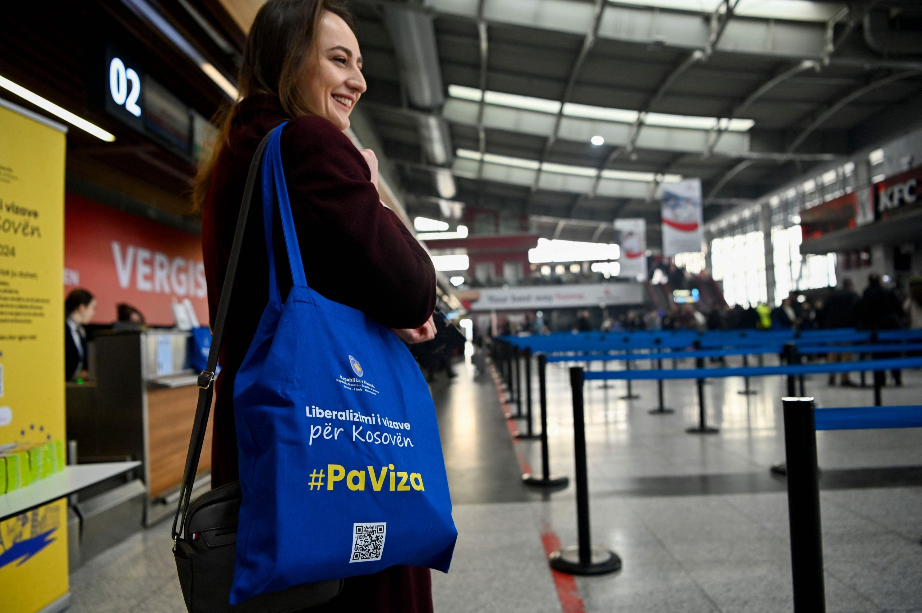 A woman holds a tote bag reading 