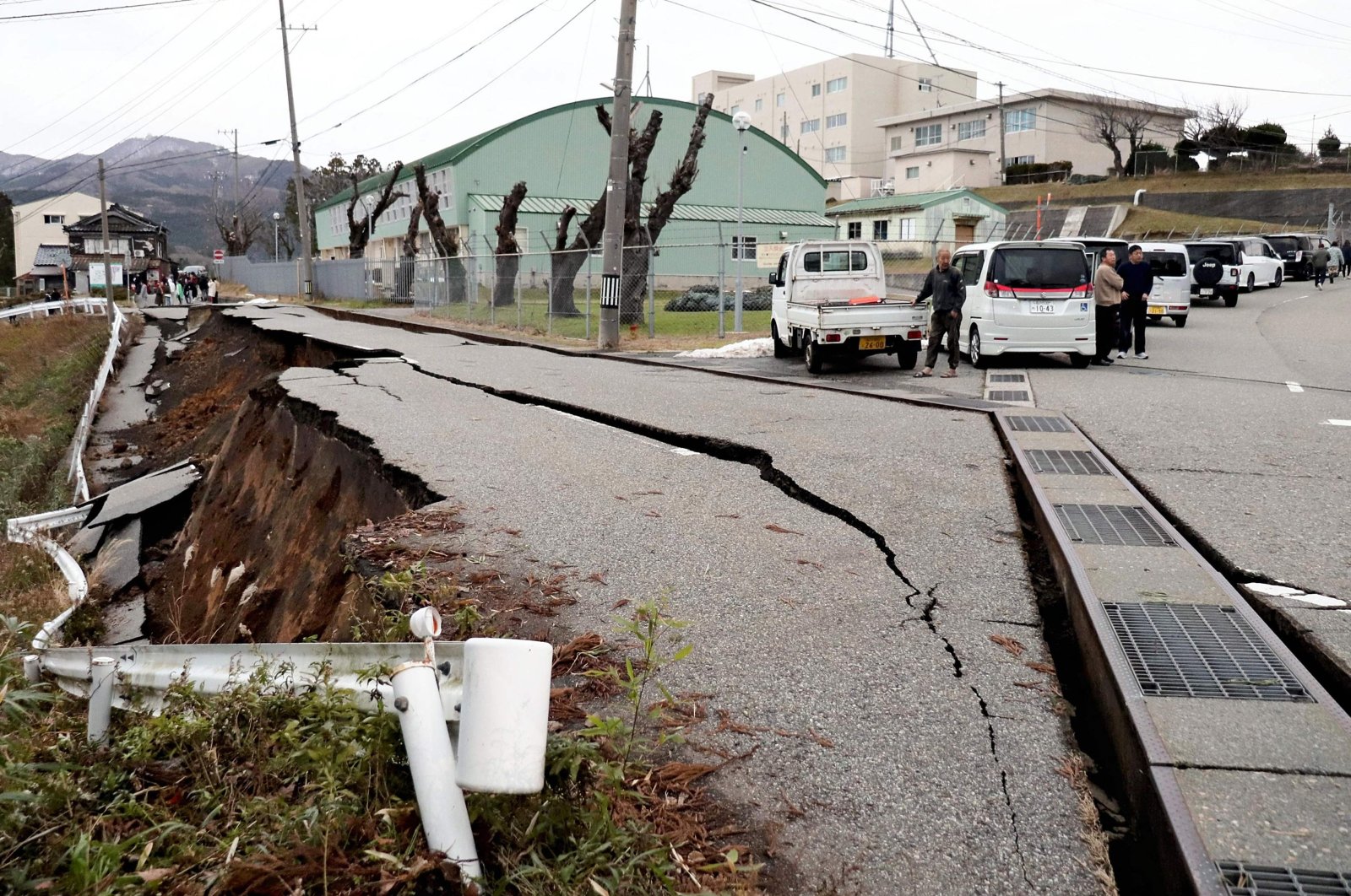  People stand next to large cracks in the pavement after evacuating into a street in the city of Wajima, Ishikawa prefecture on Jan. 1, 2024. (Photo by Yusuke FUKUHARA / Yomiuri Shimbun via AFP) 