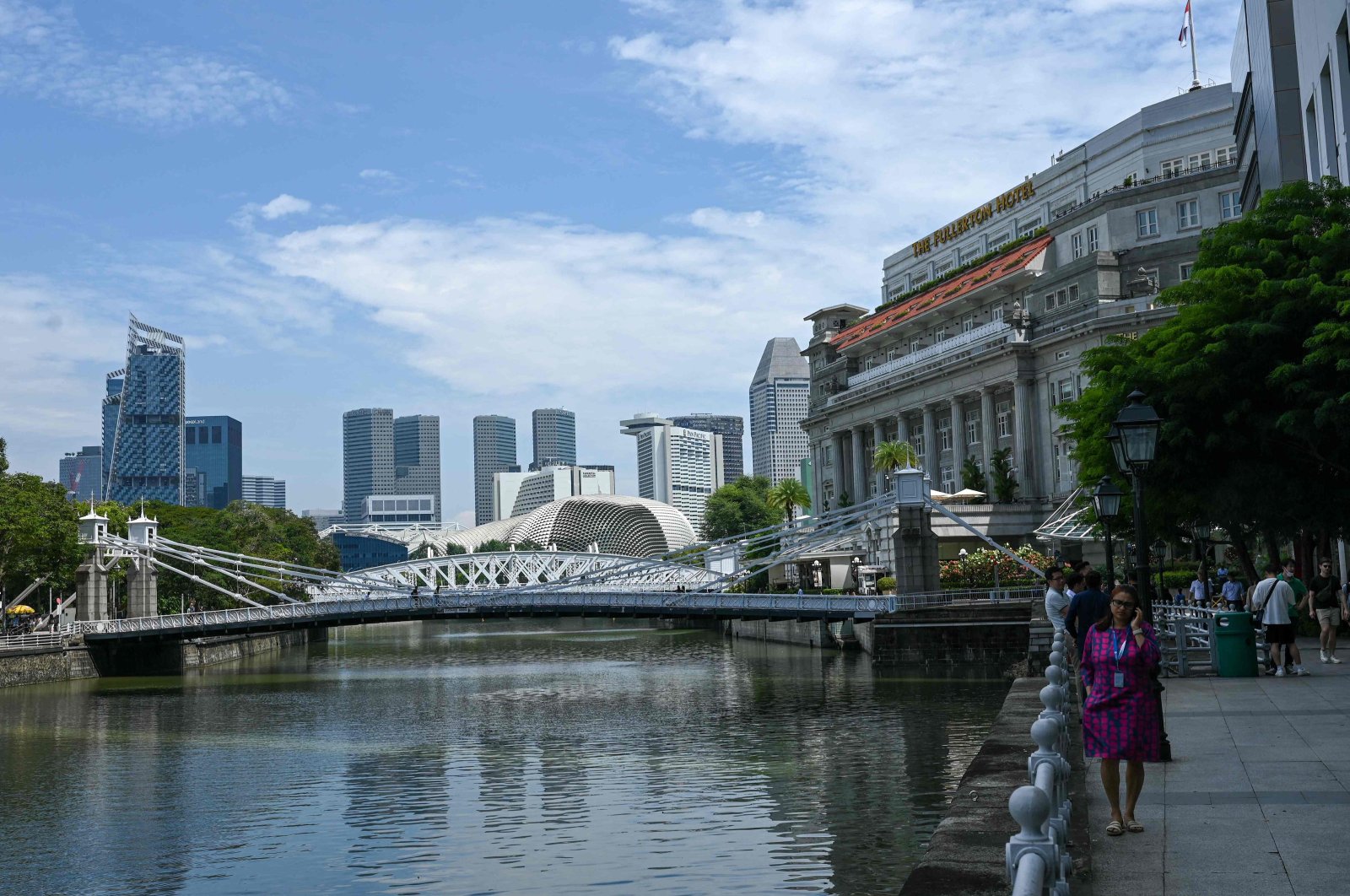 People relax next to a river at the Raffles Place financial district in Singapore, Dec. 5, 2023. (AFP Photo)