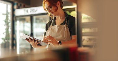 A shop owner uses a digital tablet. (Shutterstock Photo)