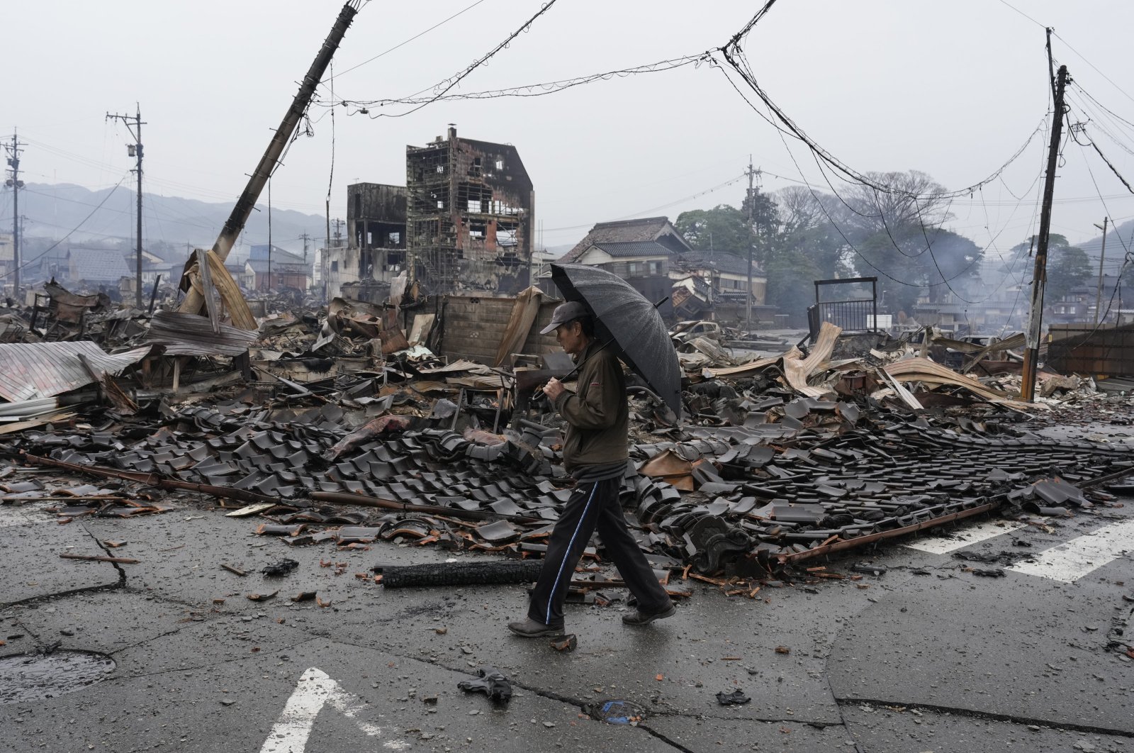 A man walks past burnt remains of a building following an earthquake in Wajima, Ishikawa Prefecture, Japan, Jan. 3, 2024. (EPA Photo)