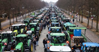 People stand beside tractors, as German farmers take part in a protest against the cut of vehicle tax subsidies, near the Brandenburg Gate in Berlin, Germany, Dec. 18, 2023. (Reuters Photo)