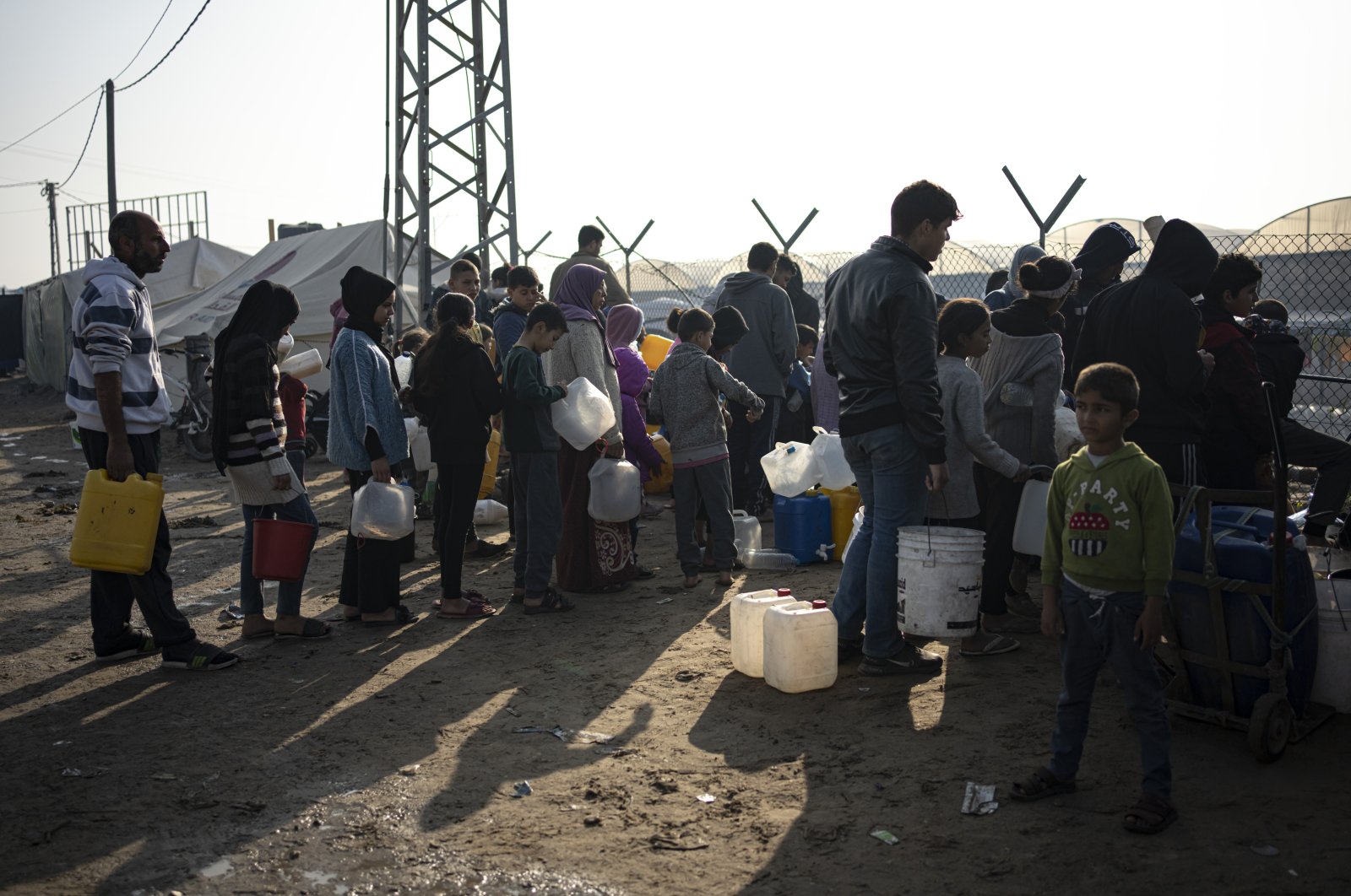 Members of the Abu Jarad family, who were displaced by the Israeli bombardment of the Gaza Strip, queue for water at a makeshift tent camp in the Muwasi area, Gaza, Palestine, Jan. 1, 2024. (AP Photo)