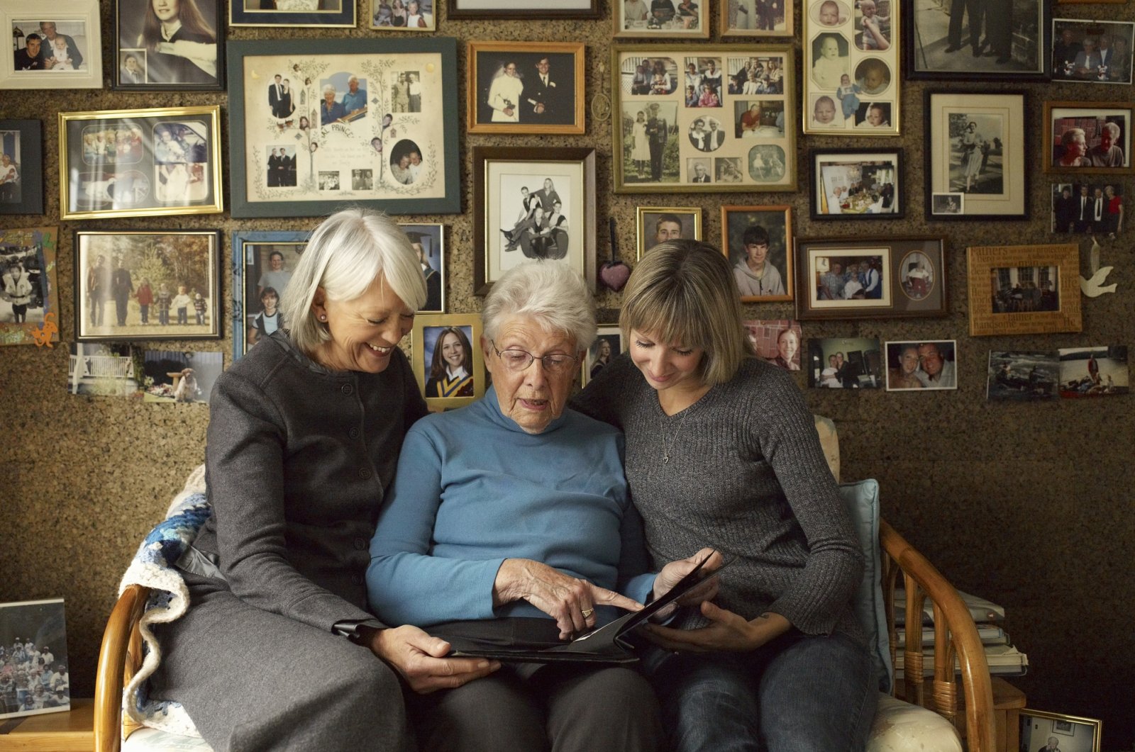 Three generations of women look at a photo album. (Getty Images Photo)