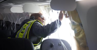 National Transportation Safety Board (NTSB) investigator-in-charge John Lovell examines the fuselage plug area of Alaska Airlines Boeing 737 Max 9, Flight 1282, which was forced to make an emergency landing with a gap in the fuselage, Portland, Oregon, U.S., Jan. 7, 2024. (The Oregonian via Reuters)
