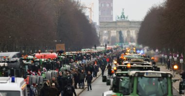 People stand beside tractors, as German farmers take part in a protest against the cut of vehicle tax subsidies, by the Brandenburg Gate, Berlin, Germany, Dec. 18, 2023. (Reuters Photo)