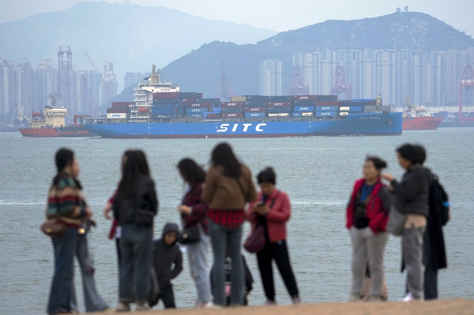 A container ship passes tourists in Xiamen in southeast China&#039;s Fujian province, Dec. 26, 2023. (AP Photo)
