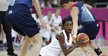 France's Emilie Gomis looks to pass as she is flanked by Britain's Stef Collins, right, and Natalie Stafford during a women's basketball game at the 2012 Summer Olympics, London, U.K., Aug. 3, 2012. (AP Photo)