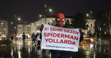 Local "Spider-Man" Ayaz Koç holds a sign reading, "The Spider-Man who visits 81 provinces hits the road," Sivas, central Türkiye, Jan. 11, 2024. (IHA Photo)