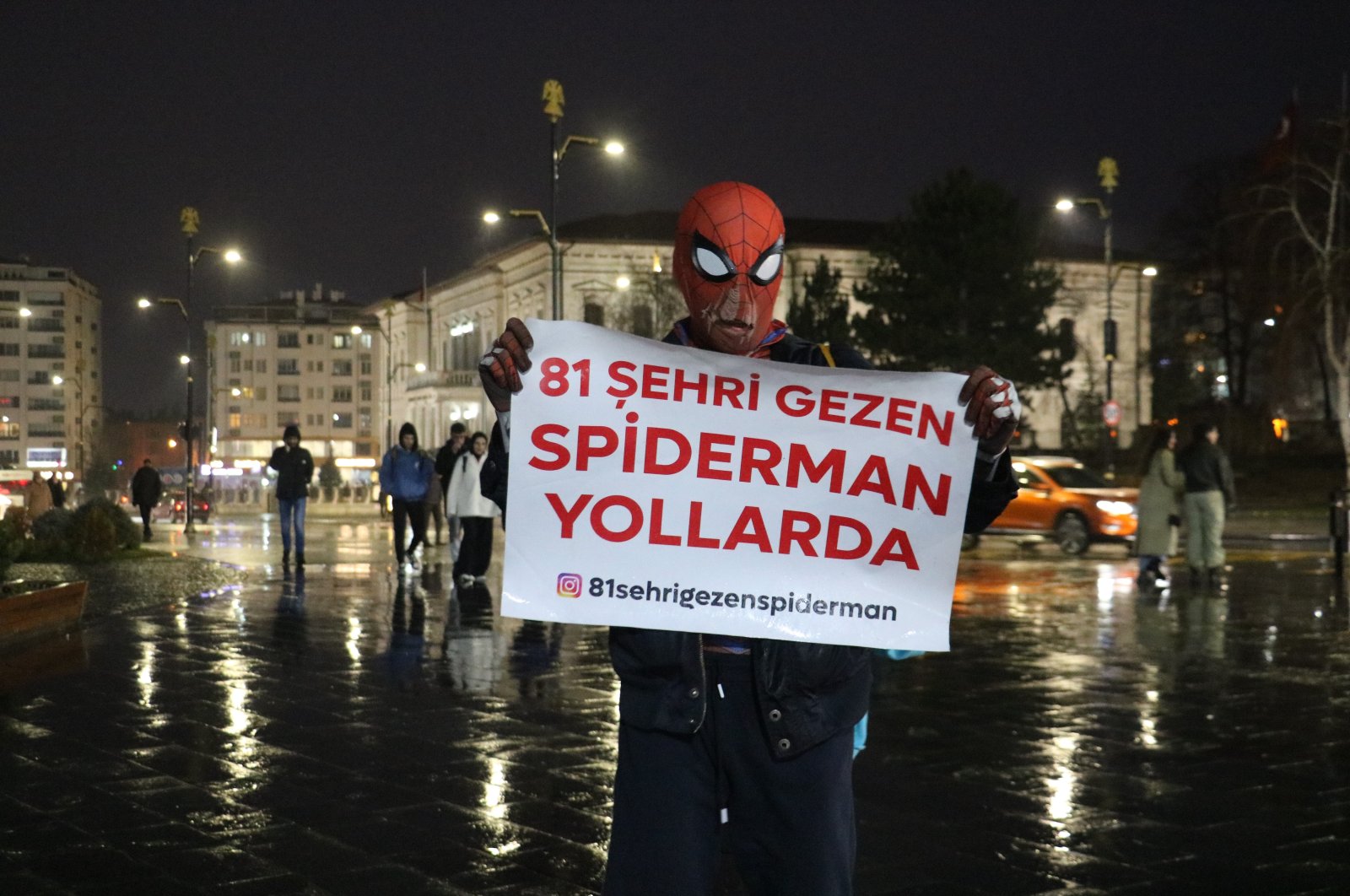 Local "Spider-Man" Ayaz Koç holds a sign reading, "The Spider-Man who visits 81 provinces hits the road," Sivas, central Türkiye, Jan. 11, 2024. (IHA Photo)