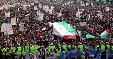 Demonstrators hold placards and wave a giant Palestinian flag during a march in solidarity with the people of Gaza in Sanaa, Yemen, Jan. 5, 2024. (AFP Photo)