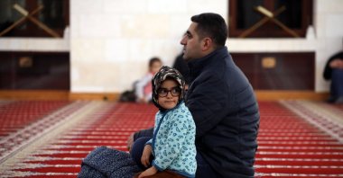 A child sits with her father in a mosque that was affected by the Feb. 6 earthquakes, Malatya, Türkiye, Jan. 12, 2024. (AA Photo)