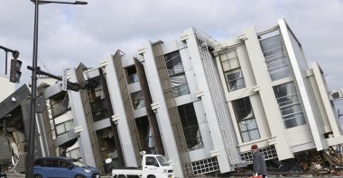 A man walks past a fallen building hit by a powerful earthquake on New Year’s Day in Wajima, Japan, Jan. 11, 2024. (AP Photo)