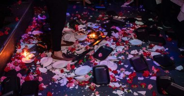 A photo shows broken plates and flowers on the floor at the feet of a singer as he performs at a Greek nightclub in the western suburbs of Athens, Greece, Jan. 7, 2024. (AFP Photo)
