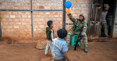 A member of the Mandalay People’s Defense Forces (MDY-PDF) playing with children near a frontline in northern Shan State, Myanmar, Dec. 10, 2023. (AFP Photo)
