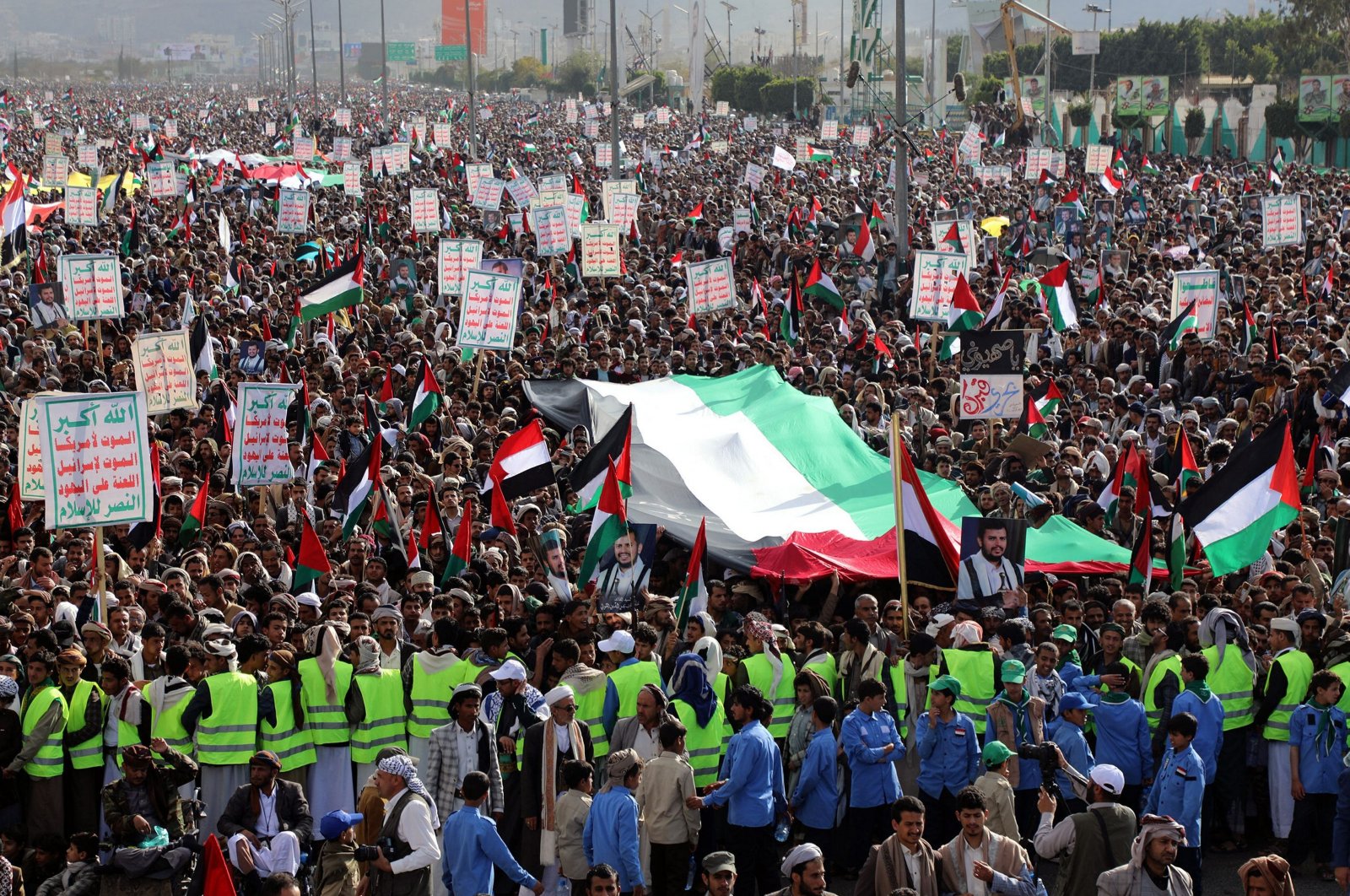 Demonstrators hold placards and wave a giant Palestinian flag during a march in solidarity with the people of Gaza in Sanaa, Yemen, Jan. 5, 2024. (AFP Photo)