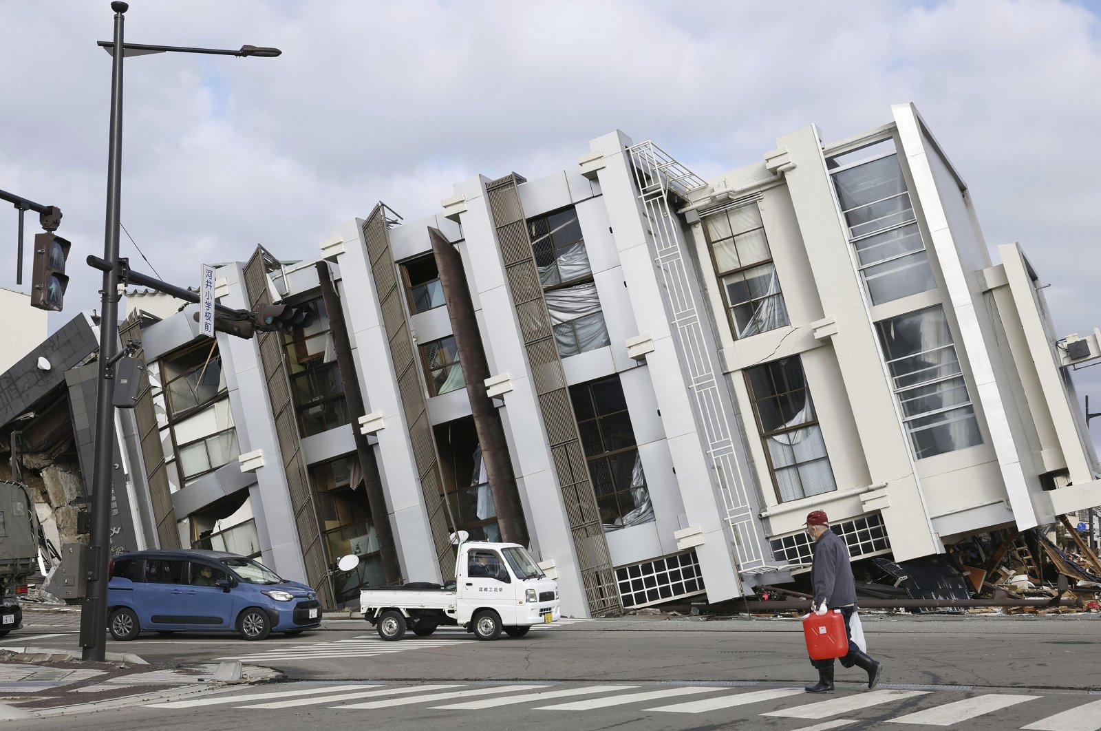 A man walks past a fallen building hit by a powerful earthquake on New Year’s Day in Wajima, Japan, Jan. 11, 2024. (AP Photo)