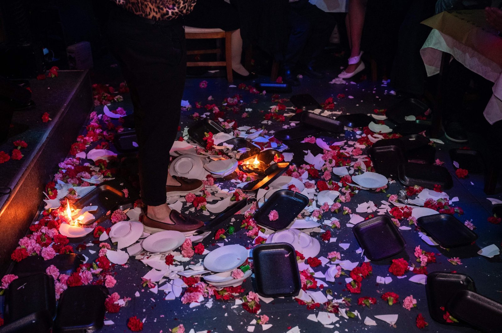 A photo shows broken plates and flowers on the floor at the feet of a singer as he performs at a Greek nightclub in the western suburbs of Athens, Greece, Jan. 7, 2024. (AFP Photo)