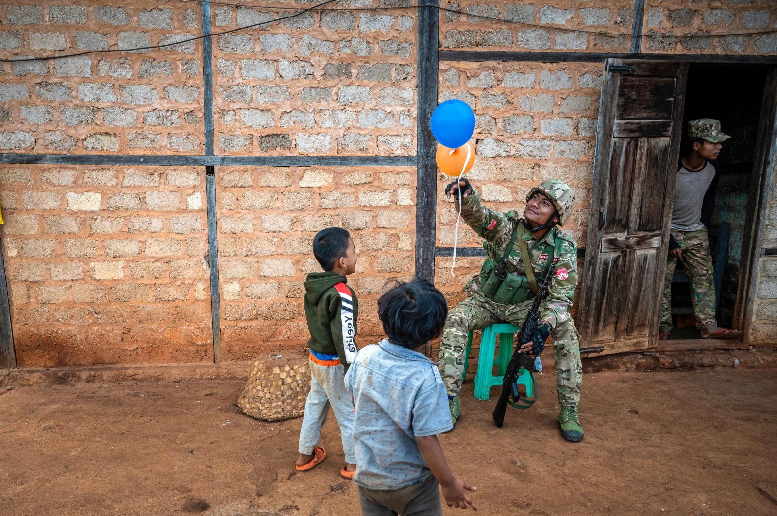 A member of the Mandalay People’s Defense Forces (MDY-PDF) playing with children near a frontline in northern Shan State, Myanmar, Dec. 10, 2023. (AFP Photo)