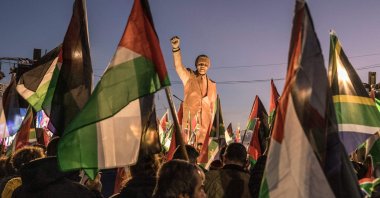 People raise flags and placards as they gather around a statue of late South African President Nelson Mandela to celebrate a landmark genocide case filed by South Africa against Israel at the International Court of Justice, in the occupied West Bank city of Ramallah, Palestine, Jan. 10, 2024.  (AFP Photo)