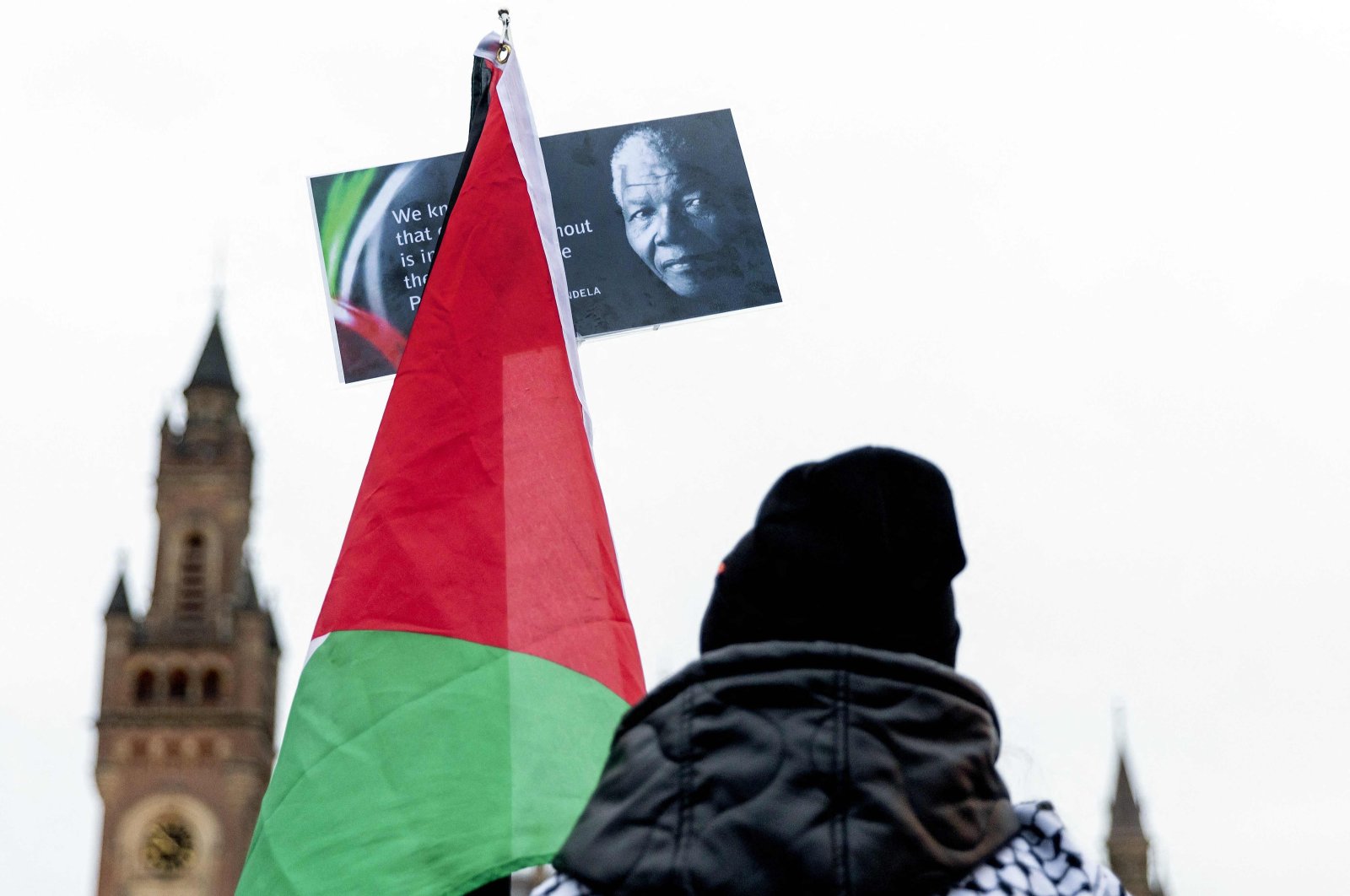 A Pro-Palestinian sympathizer holds a flag with an image of the late South African President Nelson Mandela as he takes part with others in a rally outside the International Court of Justice (ICJ) in The Hague, prior to the hearing of the genocide case against Israel, brought by South Africa, the Netherlands, Jan. 12, 2024. (AFP Photo)