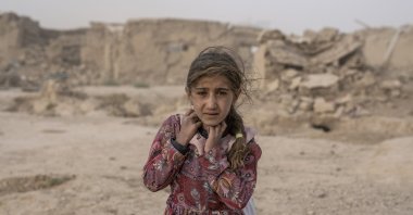 An Afghan girl carries donated aid to her tent, while she is scared from a fierce sandstorm, after an earthquake in Zinda Jan district in Herat province, western Afghanistan, Oct. 12, 2023. (AP Photo)