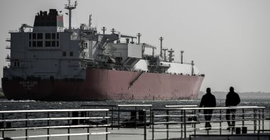 Two men watch a ship crossing the Suez Canal toward the Red Sea in Ismailia, Egypt, Dec. 22, 2023. (EPA Photo)