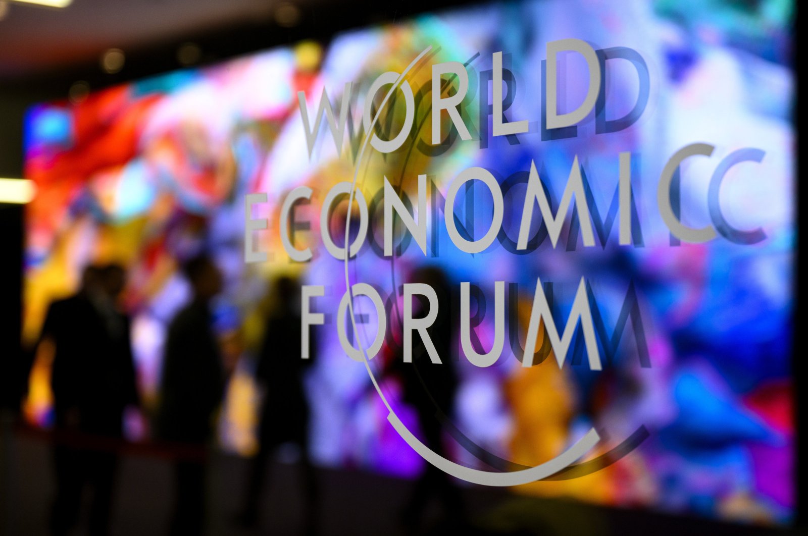 The logo of the World Economic Forum on a window of the Congress Center as participants and artificial intelligence-generated artwork by U.S.-based Turkish media artist Refik Anadol is reflected inside the center on the eve of the 54th annual meeting of the WEF in Davos, Switzerland, Jan. 14, 2024. (EPA Photo)