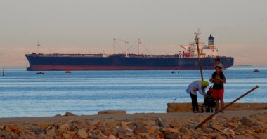 People walk on a beach as a container ship crosses the Gulf of Suez toward the Red Sea before entering the Suez Canal, in al-Ain al-Sokhna, Suez, east of Cairo, Egypt, April 24, 2017. (Reuters Photo)