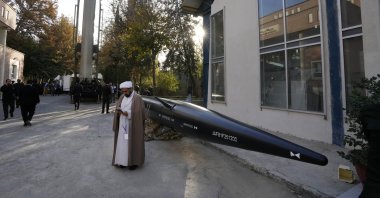 An Iranian cleric uses his cellphone while standing next to missiles displayed in an exhibition during a ceremony in Tehran, Iran, Monday, Nov. 13, 2023. (AP File Photo)