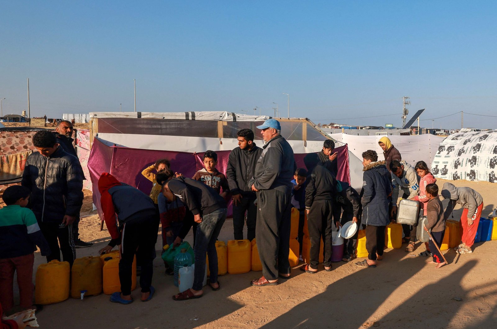 Displaced Palestinians queue for water at a makeshift tent camp by the beach in Rafah near the border with Egypt in the southern Gaza Strip on Jan. 16, 2024. (AFP Photo)