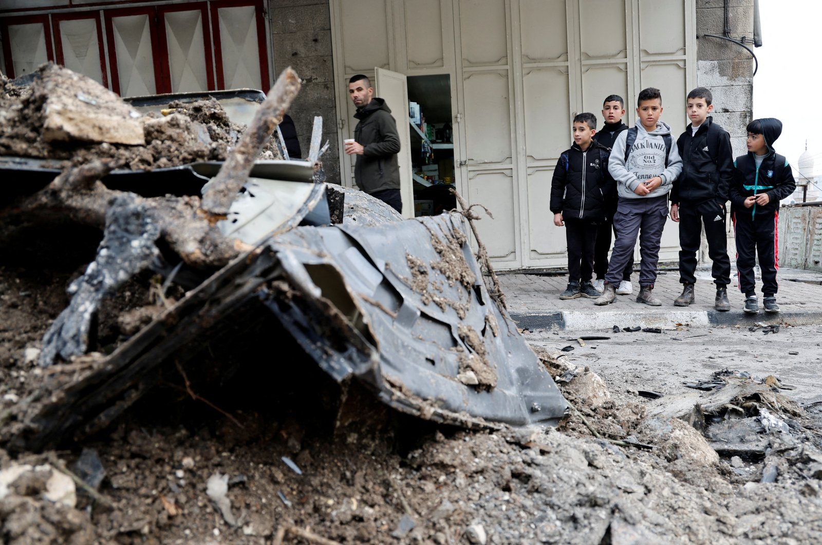 A Palestinian man and children inspect the site of an Israeli strike on a car in Nablus, in the Israeli-occupied West Bank, Palestine, Jan. 17, 2024. (Reuters Photo)