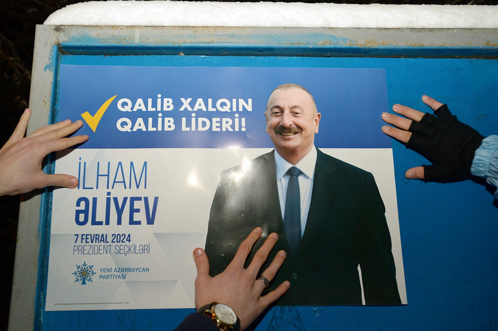 Electoral officials stick up a campaign poster of Azerbaijani President and presidential candidate Ilham Aliyev on the first day of the official campaigning ahead of the snap presidential election, which will be held on February, in Baku, Azerbaijan, Jan. 15, 2024. (AFP Photo)