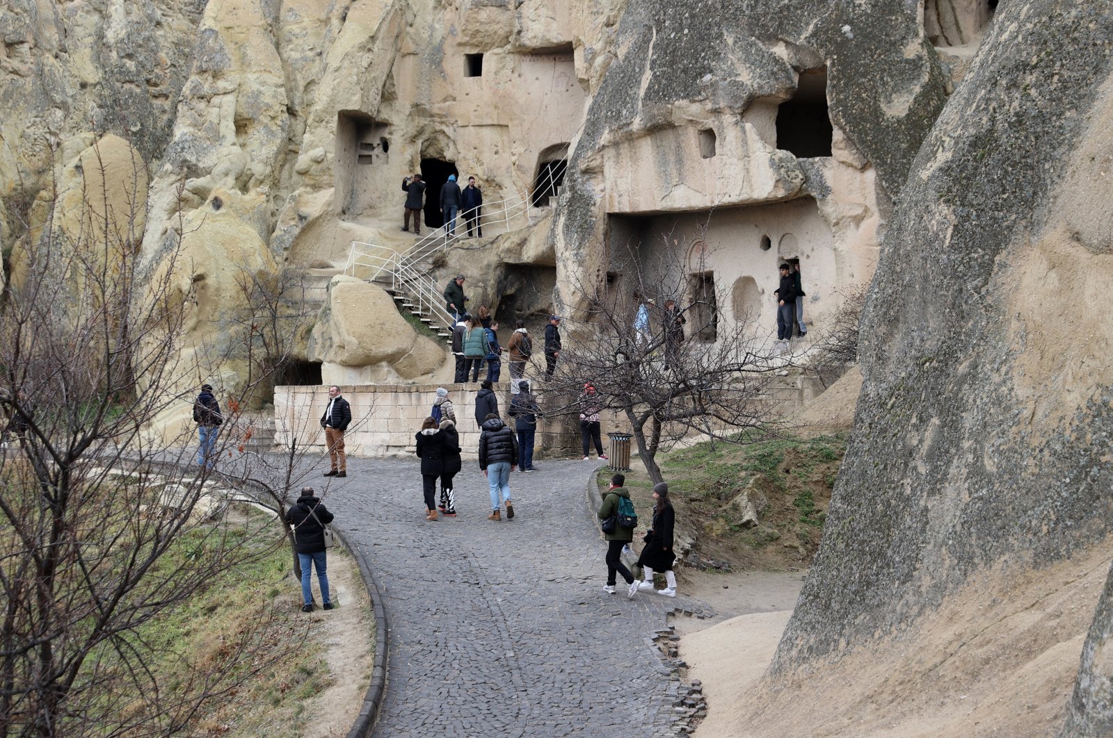 Visitors walk on the path close to carved rock formations typical for the Cappadocia region, Nevşehir, central Türkiye, Jan. 3, 2024. (AA Photo)