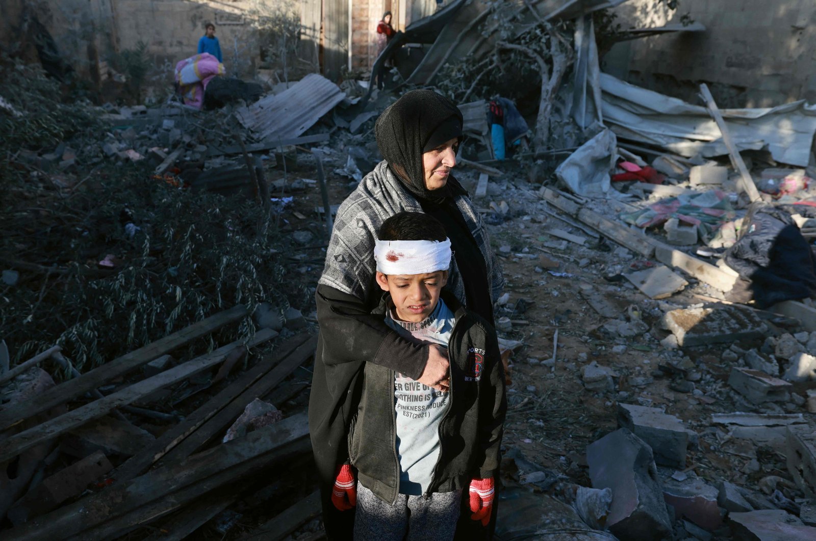 A Palestinian woman embraces a lightly injured boy as they check the rubble of a building following Israeli bombardment, Rafah, southern Gaza Strip, Palestine, Jan. 18, 2024. (AFP Photo)