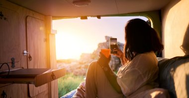 A woman enjoying the sunset inside a camper van. (Getty Images Photo)
