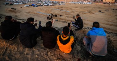Displaced Palestinians using eSIM cards attempt to get a signal in order to contact their relatives on a hill facing their makeshift camp in Rafah, on the southern Gaza Strip on the border with Egypt, Jan. 19, 2024. (AFP Photo)