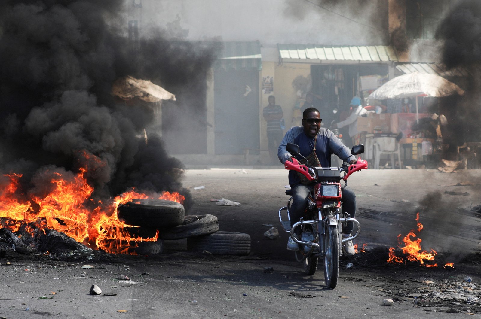 A motorcyclist reacts while driving through a burning barricade, one of many across several neighbourhoods that forced residents to take shelter, Port-au-Prince, Haiti, Jan. 18, 2024. (Reuters Photo)