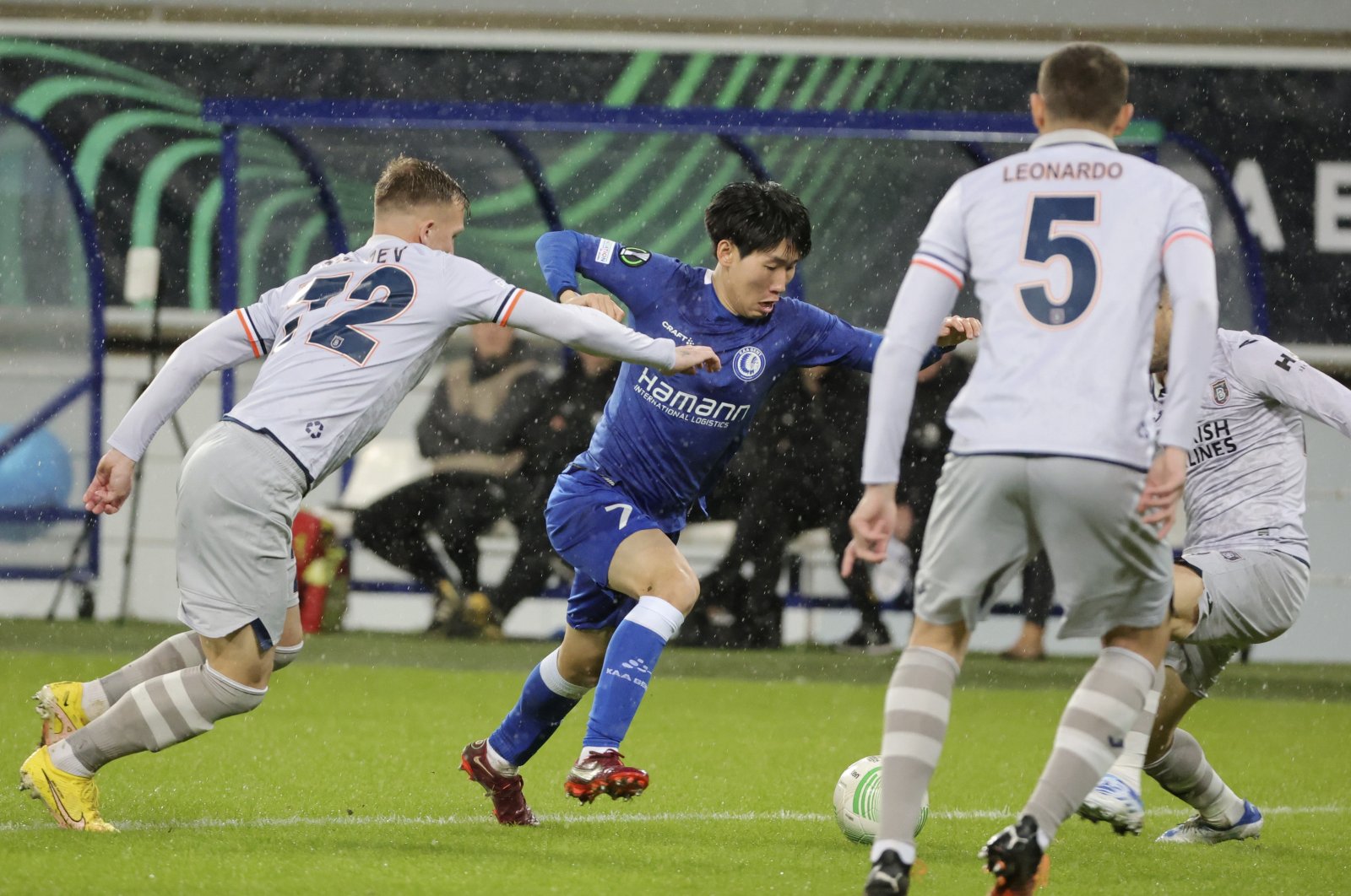 Istanbul Başakşehir&#039;s Eden Karzev (L) fights for the ball with Gent&#039;s Hyunseok Hong (C) during the Europa Conference League round of 16 first leg match at KAA Gent stadium, Ghent, Belgium, March 9, 2023. (AP Photo)
