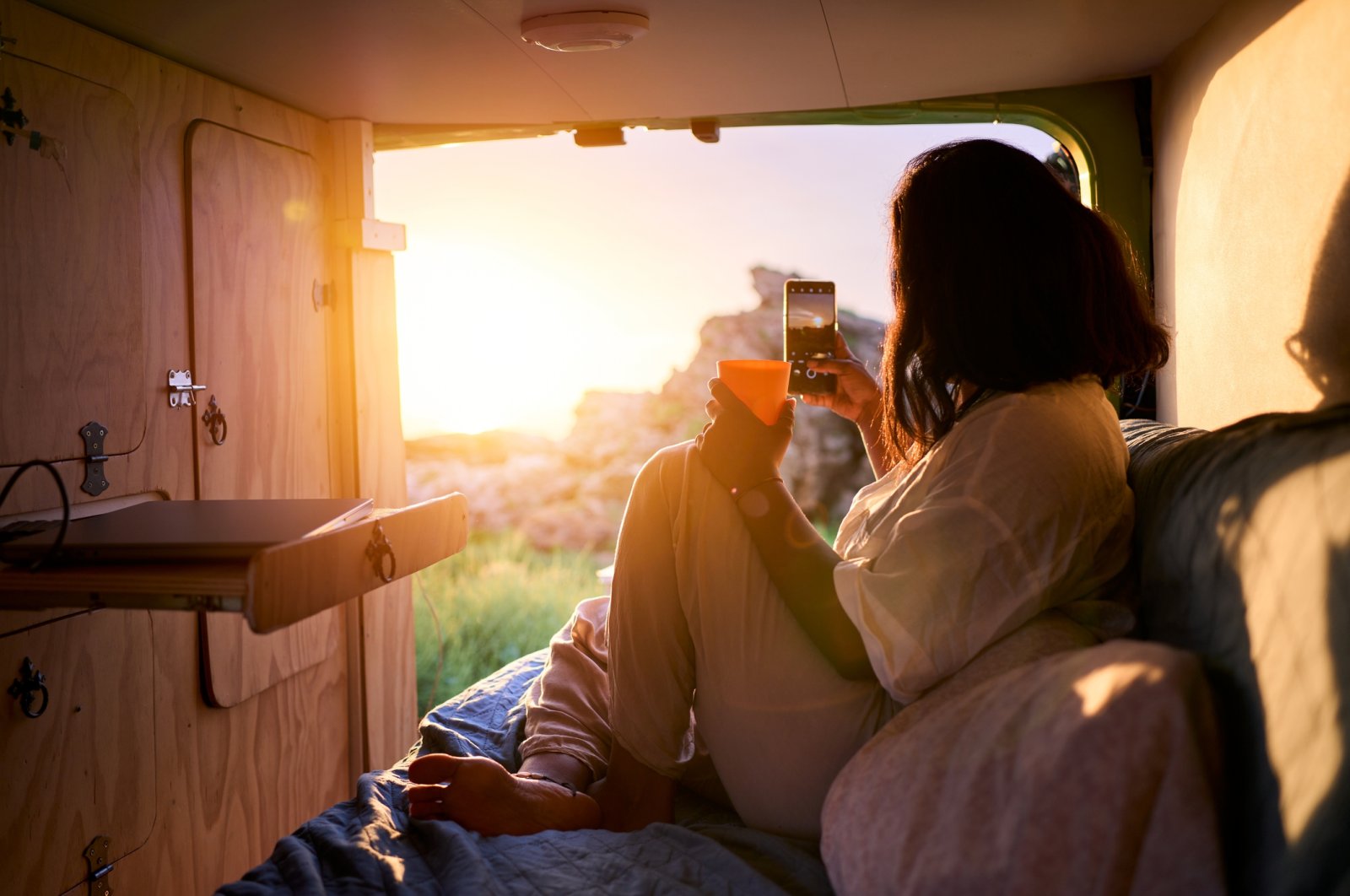 A woman enjoying the sunset inside a camper van. (Getty Images Photo)