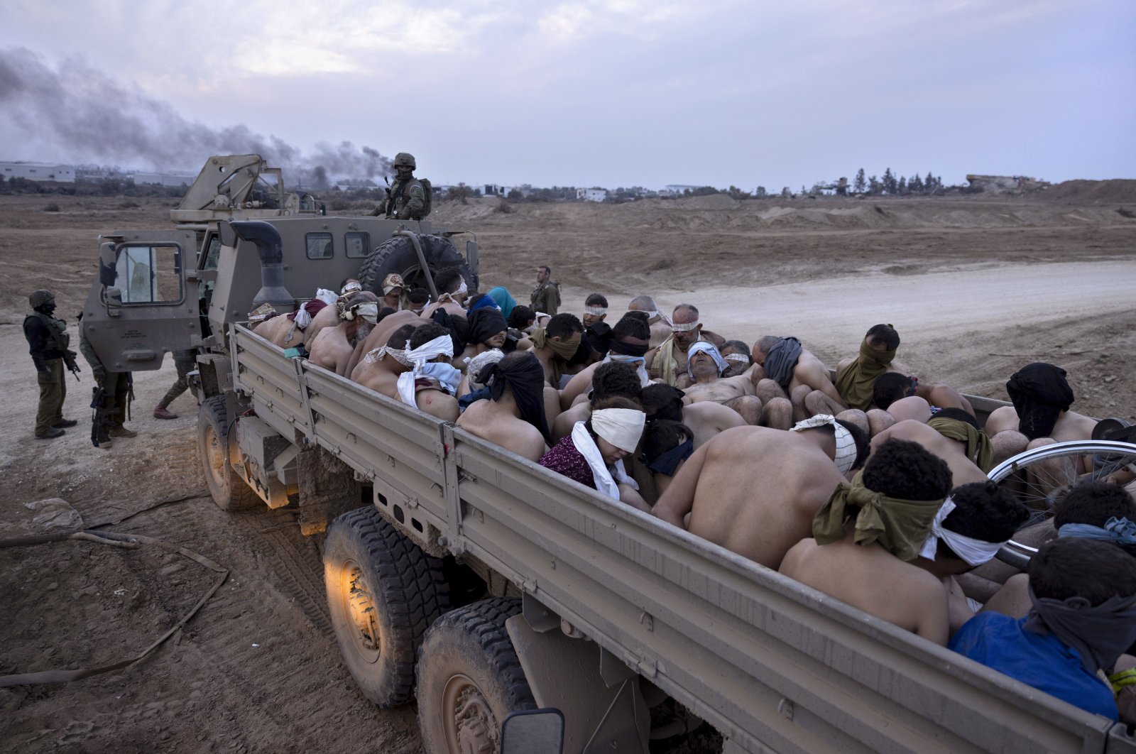 Israeli soldiers stand by a truck packed with bound and blindfolded Palestinian detainees, Gaza, Palestine, Dec. 8, 2023. (AP Photo)