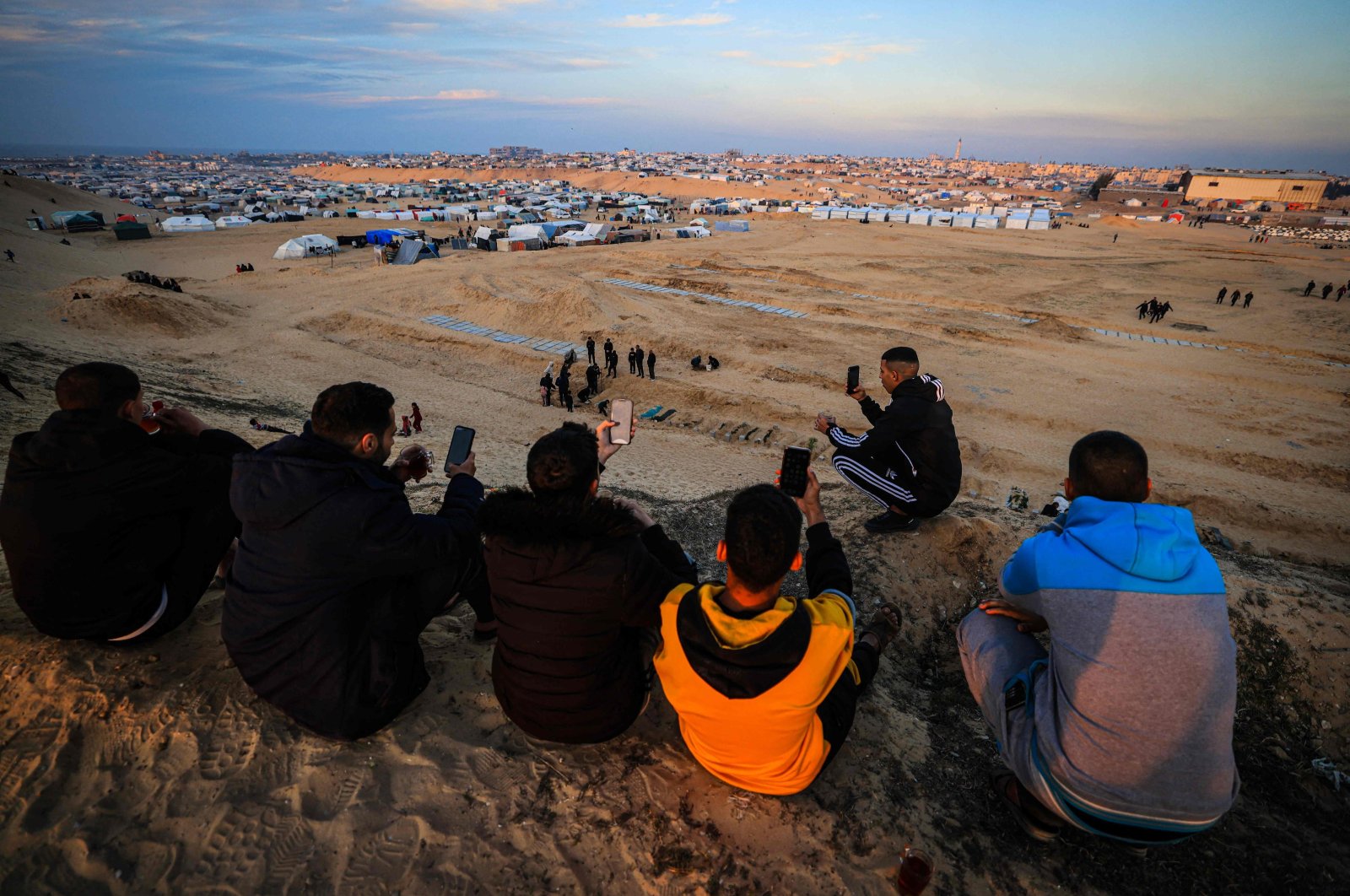 Displaced Palestinians using eSIM cards attempt to get a signal in order to contact their relatives on a hill facing their makeshift camp in Rafah, on the southern Gaza Strip on the border with Egypt, Jan. 19, 2024. (AFP Photo)