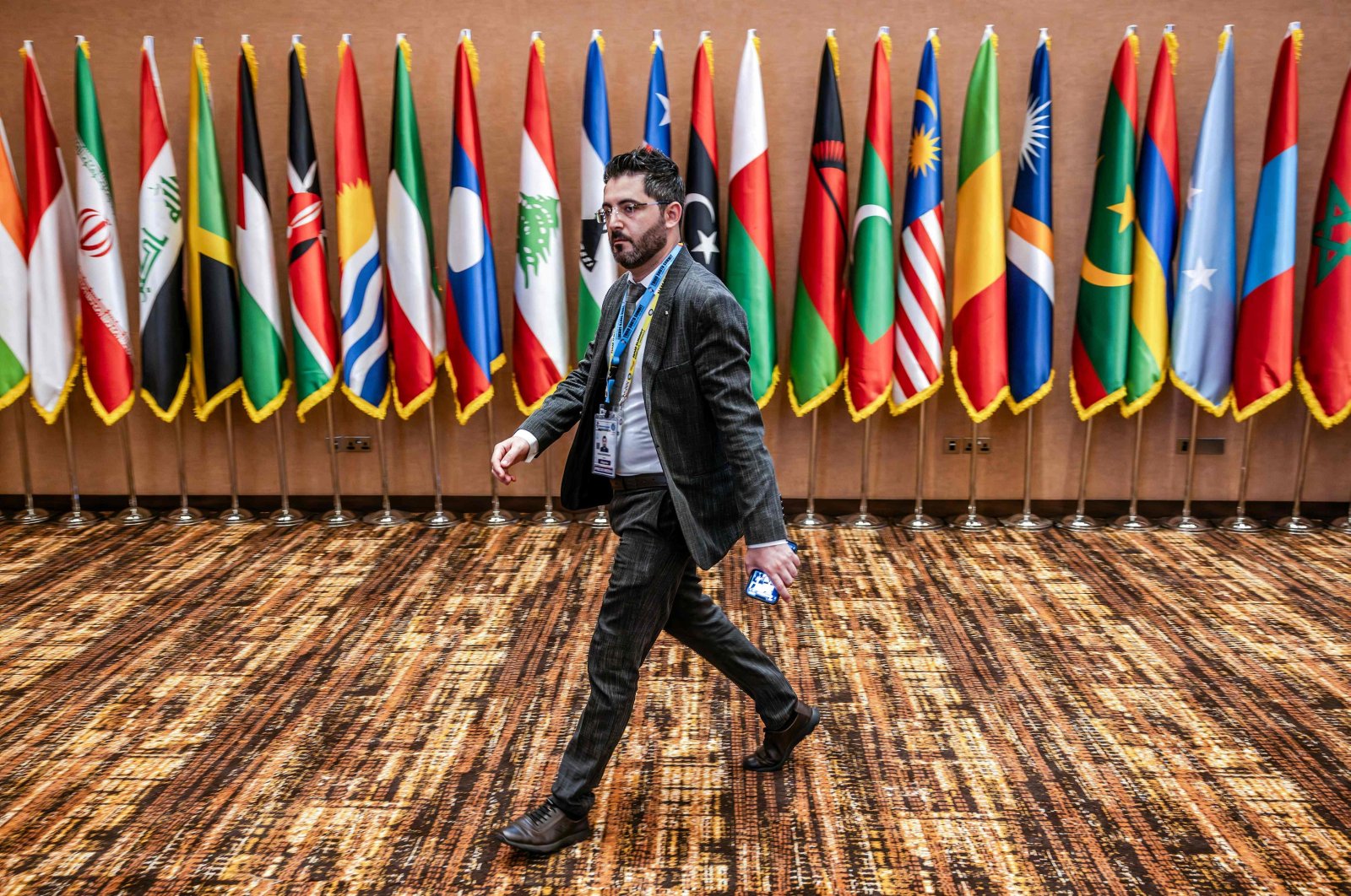 A delegate walks past member flags during the 19th Non-Aligned Movement (NAM) Summit in Kampala, Uganda, Jan. 20, 2024. (AFP Photo)