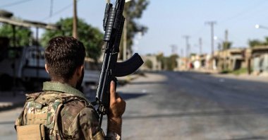 A PKK/YPG terrorist stands guard along a road as others deploy to impose a curfew in the town of al-Busayrah in the Deir el-Zour province, northeastern Syria, Sept. 4, 2023. (AFP Photo)