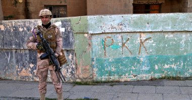 Iraqi army soldier stands next to the graffiti left by an affiliate of the PKK, in Sinjar, Iraq, Dec. 4, 2020. (AP Photo)