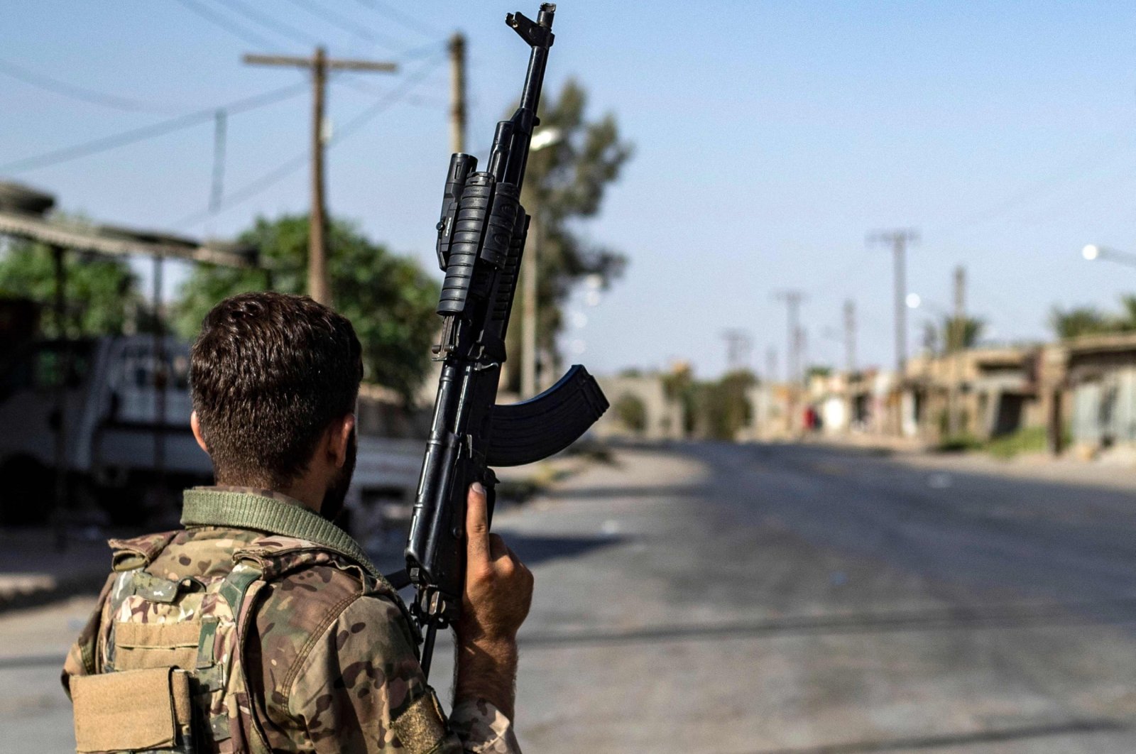 A PKK/YPG terrorist stands guard along a road as others deploy to impose a curfew in the town of al-Busayrah in the Deir el-Zour province, northeastern Syria, Sept. 4, 2023. (AFP Photo)
