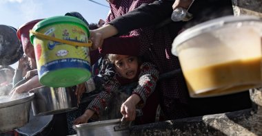 A displaced Palestinian little girl holds up her empty metal pot as she waits with others to receive food aid provided by a Palestinian youth group in the Rafah refugee camp, Southern Gaza Strip, Jan. 25, 2024. (EPA Photo)
