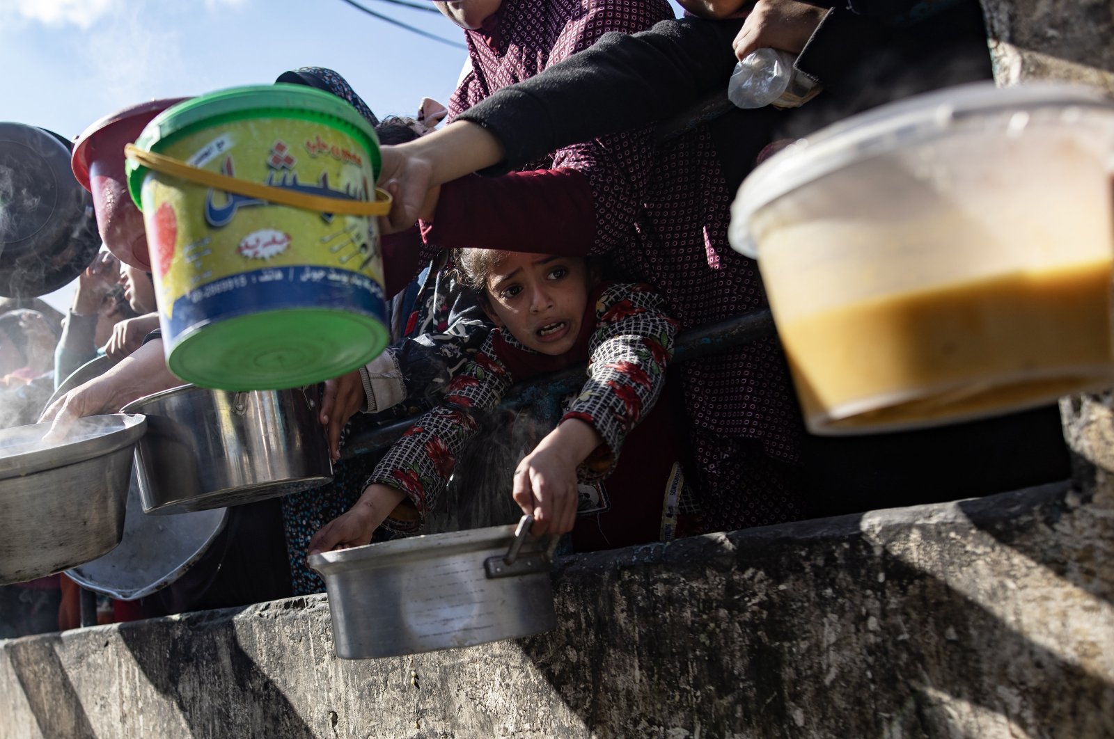 A displaced Palestinian little girl holds up her empty metal pot as she waits with others to receive food aid provided by a Palestinian youth group in the Rafah refugee camp, Southern Gaza Strip, Jan. 25, 2024. (EPA Photo)